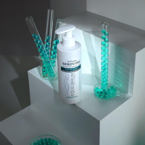 Gerovital Equilibrium Body Sculpting Massage Oil bottle beside turquoise beads in glass tubes