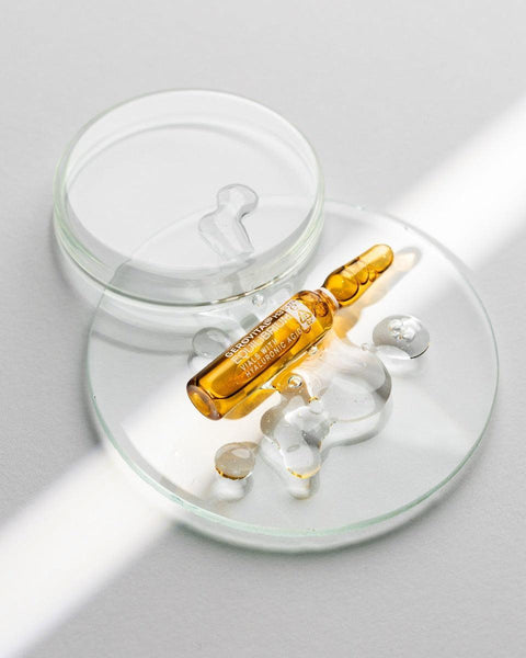Gerovital Hyaluronic Acid 4D amber ampoule on glass dishes beside clear gel droplets