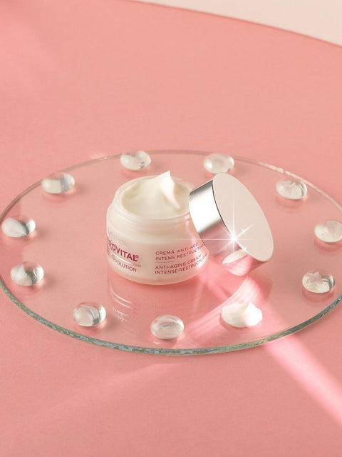 Open Gerovital H3 Evolution Intense Restructuring Anti-Aging Cream jar on a glass tray against a pink background