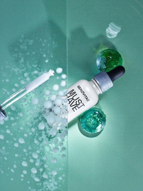 Gerovital Must Have firming serum bottle and dropper with laboratory flasks on green