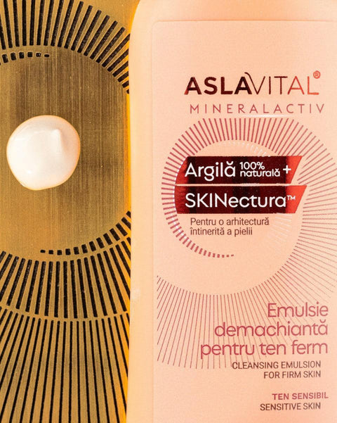 Close-up of Aslavital Cleansing Emulsion bottle beside a white cream droplet on a gold-colored surface