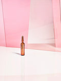 Gerovital H3 Derma+ Anti Hair Loss Treatment amber ampoule against pink panels
