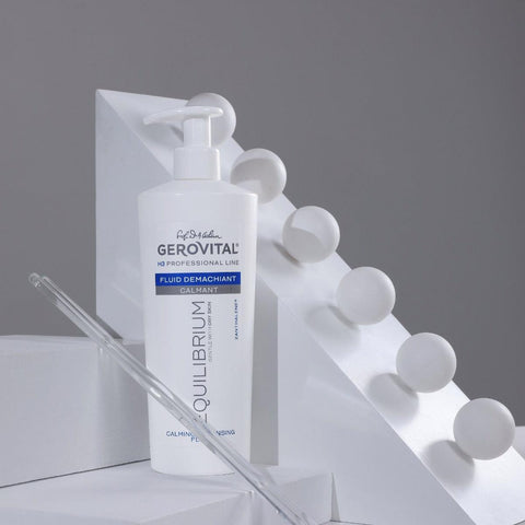 Gerovital H3 Equilibrium Soothing Cleansing Fluid pump bottle beside white geometric blocks and a glass pipette