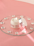 Open Gerovital H3 Evolution Intense Restructuring Anti-Aging Cream jar on a glass tray against a pink background