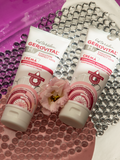 Gerovital Anti Cellulite Cream and Moisturising Firming Body Cream tubes on glass beads beside a pink flower