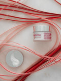 Gerovital H3 Evolution hyaluronic acid cream jar and cream swatch among red and pink decorative strips