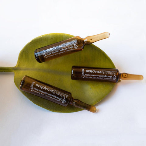 Three Gerovital Hair Expert Anti-Dandruff ampoules resting on a green leaf