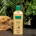 Gerovital Hair Expert Keratin Regenerating Shampoo bottle beside wood and green foliage