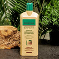 Gerovital Hair Expert Keratin Regenerating Shampoo bottle beside wood and green foliage