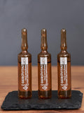 Three Gerovital Men Anti Hair Loss ampoules standing on black slate